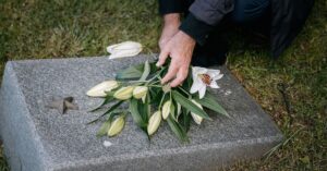 Person placing white flowers on gravestone representing Moses Lake wrongful death case